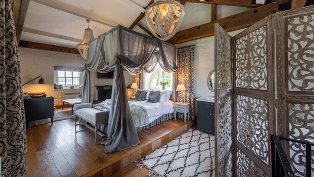 Ein Schlafzimmer mit Himmelbett, einer Kronleuchter und einer verzierten Eingangstür.