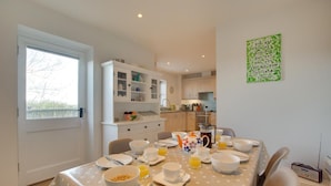 Un coin repas avec une table mise pour le petit-déjeuner, une cuisine en arrière-plan et un panneau vert sur le mur.