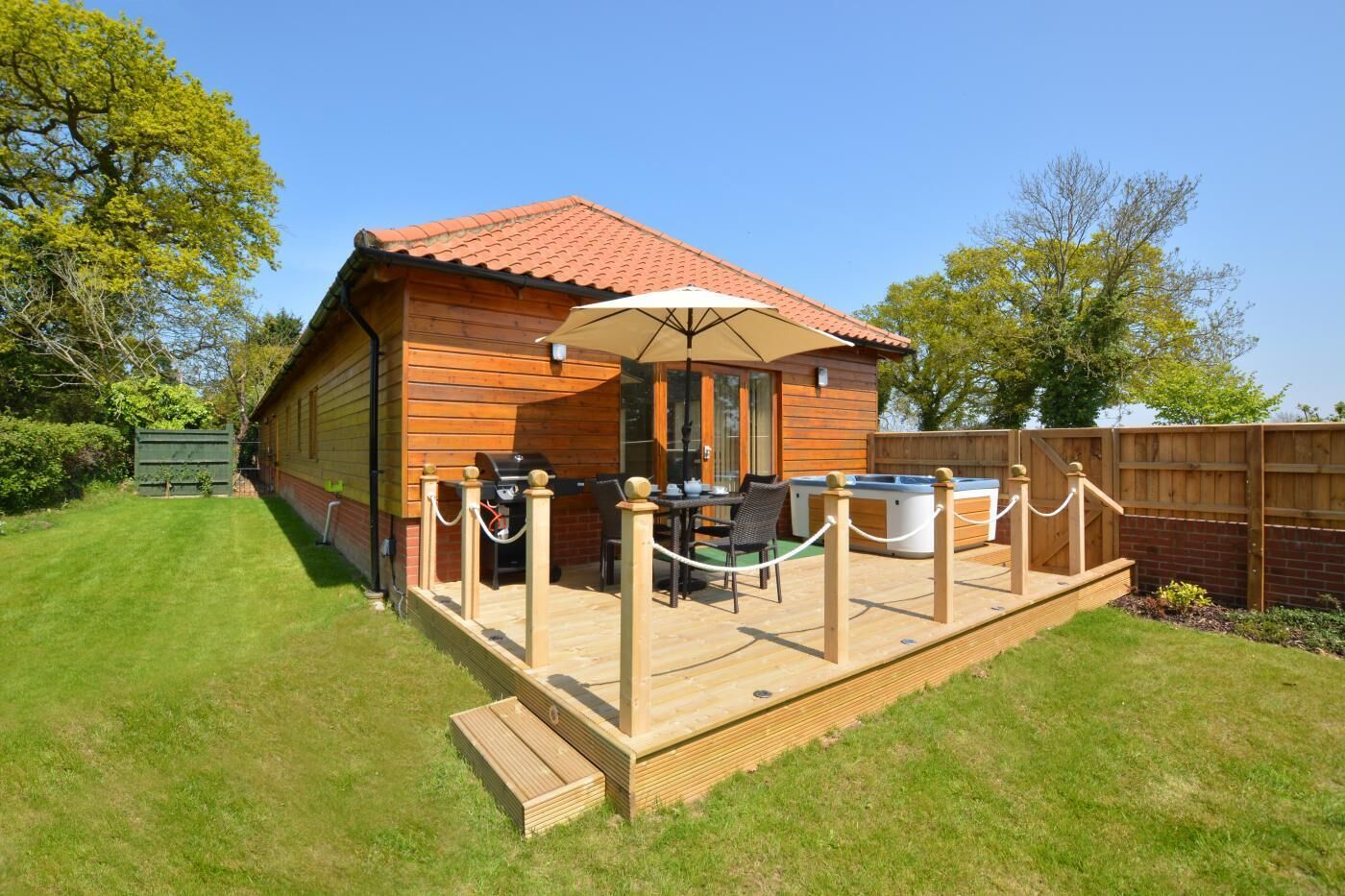 Eine Holzhütte mit Terrasse, Grillplatz und Whirlpools.