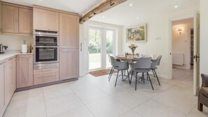 Eine moderne Küche mit Holzausstattung, einem eingebauten Backofen und einem Essbereich mit Tisch und Stühlen.