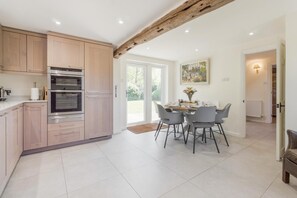 Une cuisine moderne avec des meubles en bois, un four encastré et un coin repas comprenant une table et des chaises.