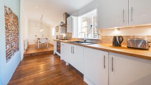 Eine moderne Küche mit weißen Schränken, einer Holz Arbeitsplatte und einem Fenster, das für natürliches Licht sorgt.