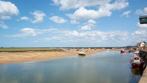 Eine Küstenlandschaft mit vertäuten Booten, einem Sandstrand und blauem Himmel.