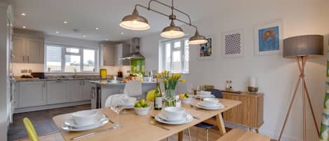 Une cuisine moderne dotée d’un îlot central, d’une table à manger pour quatre personnes et d’un grand lampadaire.