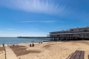 A beach with a pier extending into the water, a boardwalk with a restaurant, and people relaxing on the sand. - 2 Bed in Felixstowe (oc-hideo) (Felixstowe)