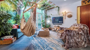 Ein gemütliches Wohnzimmer mit Hängesessel, Sofa und Fernseher.