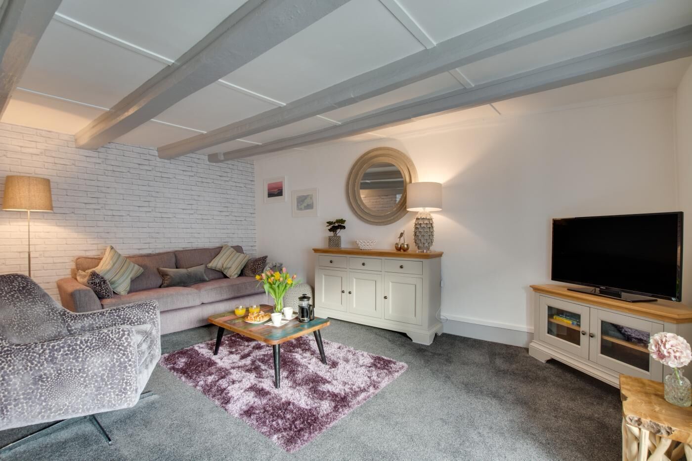 Ein Wohnzimmer mit Sofa, Couchtisch, Fernseher und Kamin.