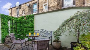 Eine Terrasse mit Korbmöbeln, einem Tisch mit zwei Gläsern Orangensaft und einer Buddha-Statue.