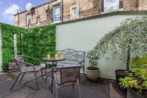 A patio with wicker furniture, a table with two glasses of orange juice, and a Buddha statue.