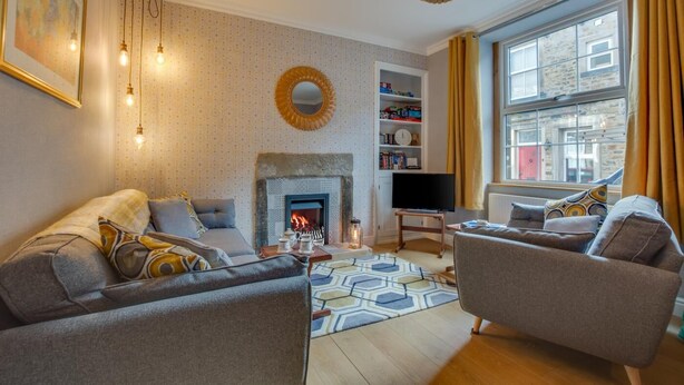 Ein Wohnzimmer mit Kamin, zwei Sofas, einem Couchtisch, einem Bücherregal und einem Fernseher.