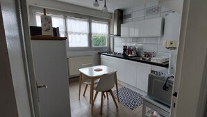 Une cuisine de taille réduite comprenant une table à manger, des chaises, un réfrigérateur et un four à micro-ondes.
