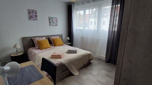 Une chambre à coucher bien rangée, avec un lit, des tables de chevet, une chaise et une lampe.