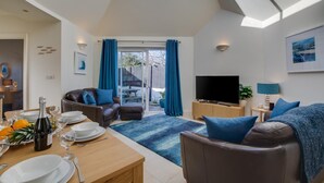 Een moderne woonkamer met een televisie, bank en eethoek.