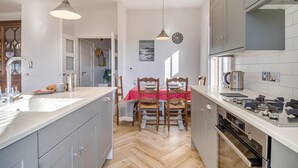 Una cuina moderna amb armaris grisos, una illa central i una zona de dinar amb estovell vermell.