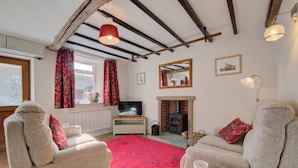 A cozy living room with a fireplace, two armchairs, a television, and a red rug. - 2 Bed in Gayle (oc-ds912) (Hawes)