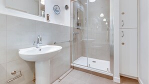 Et moderne badeværelse med en hvid vask, en glas brusekabine og et skab med lås.