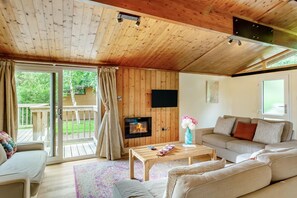 A wooden interior with a sofa, a TV, and a fireplace.