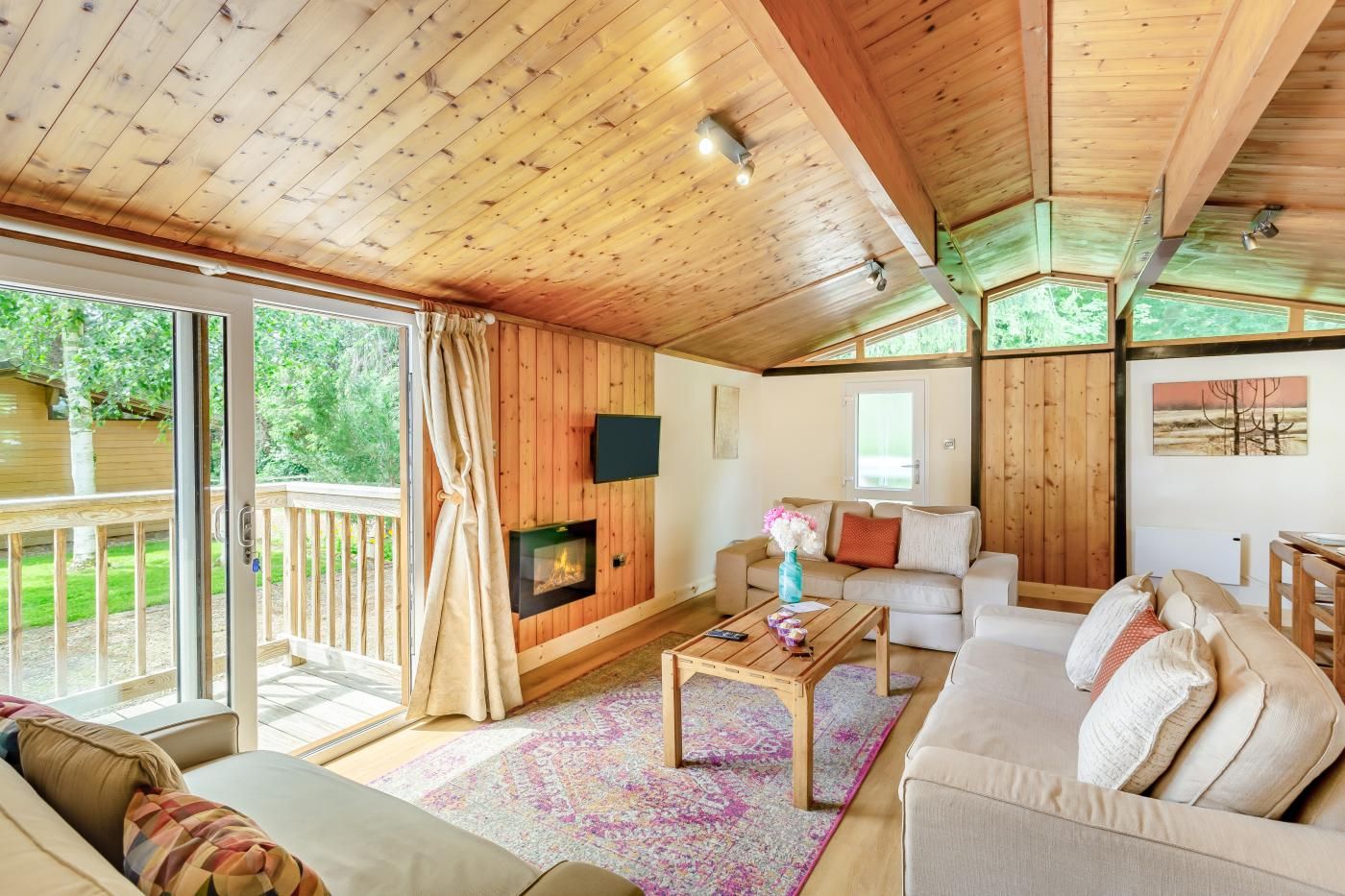 A cozy cabin interior with a fireplace, a sofa, a coffee table, and a television.