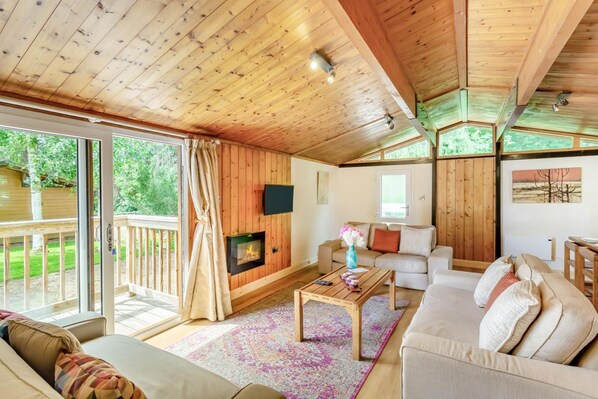 A cozy cabin interior with a fireplace, a sofa, a coffee table, and a television.
