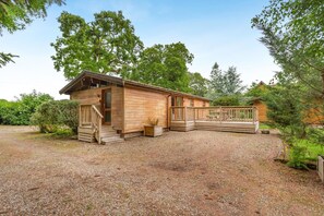 Une cabane en bois avec un porche, une terrasse et une allée gravillonnée.