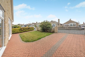 A residential area with a paved driveway, a well-maintained lawn, and houses with visible chimneys. - 2 Bed in Staithes (oc-wa071) (Staithes)