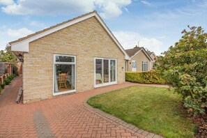 A two-story house with a brick exterior, large windows, and a well-maintained lawn. - 2 Bed in Staithes (oc-wa071) (Staithes)