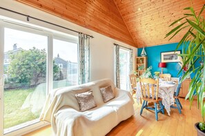 A cozy room with a sofa, dining table, chairs, and a large window with a view of the outdoors. - 2 Bed in Staithes (oc-wa071) (Staithes)