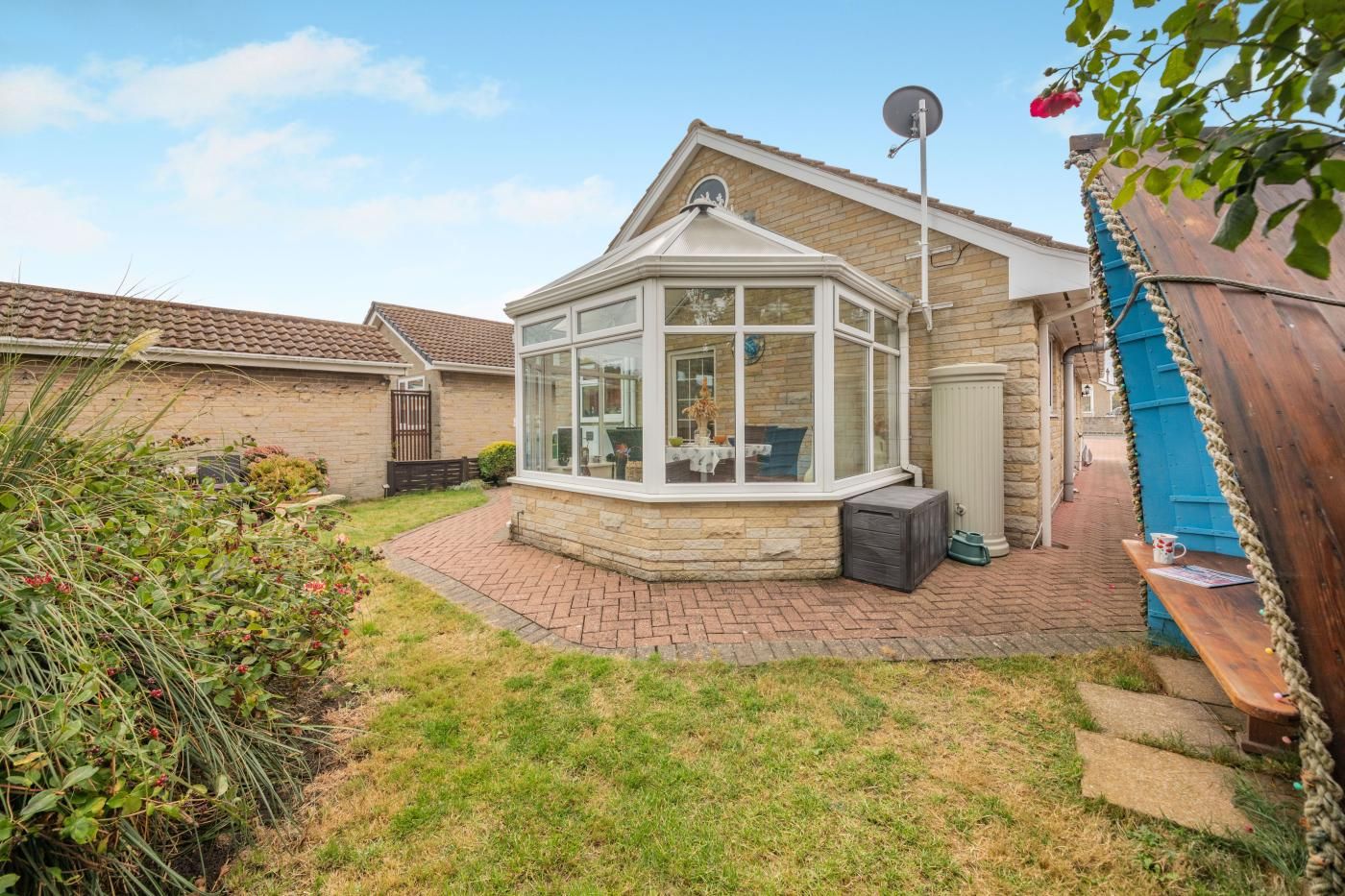 A house with a conservatory, a brick pathway, and a garden.