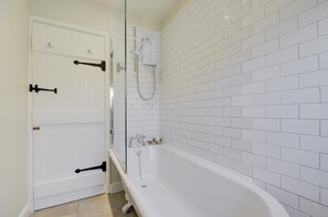 A bathroom with white tiled walls, a white bathtub, and a glass-enclosed shower area. - 2 Bed in Blakeney (oc-1977) (Blakeney)