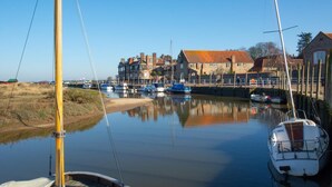 Een rustige haven met aangemeerde boten, een zandstrand en gebouwen op de achtergrond.