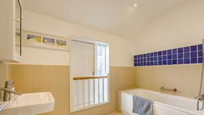 A bathroom with a sink, a bathtub, and a window. - 4 Bed in Southwold (oc-hswall) (Southwold)