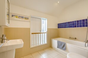 A bathroom with a sink, a bathtub, and a window.