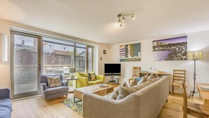 Una sala moderna con un sofá, sillones, una mesa de centro, un televisor y una zona de comedor con sillas y una mesa.