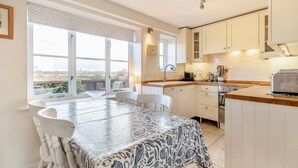 A kitchen with a dining table, chairs, and a view of the outdoors. - 3 Bed in Southwold (oc-hshore) (Southwold)