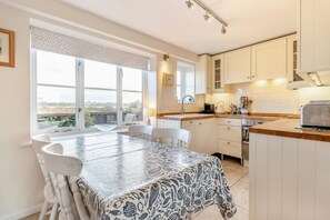 A kitchen with a dining table, chairs, and a view of the outdoors. - 3 Bed in Southwold (oc-hshore) (Southwold)