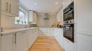Una cocina moderna con armarios blancos, horno empotrado y ventana con plantas.