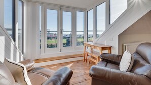 Tilava huone, jossa on suuret ikkunat, puinen työpöytä ja nahkasohvat.