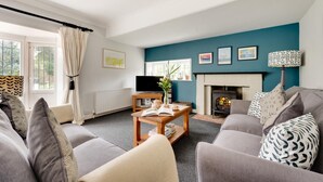 A living room with a sofa set, a fireplace, a television, and a bookshelf. - 2 Bed in Walberswick (oc-hstone) (Walberswick)