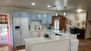 Una cocina moderna con una isla central, armarios blancos y un arco de ladrillo.