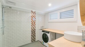 A modern bathroom with a shower, a washing machine, and a sink. - Endless Horizon - Kingscliff Beachside Unit - Min. 3 Night Stays (Kingscliff)