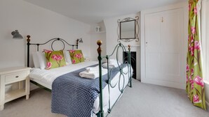 Een keurig opgemaakt slaapkamer met een bed, nachtkastje en een spiegel aan de muur.