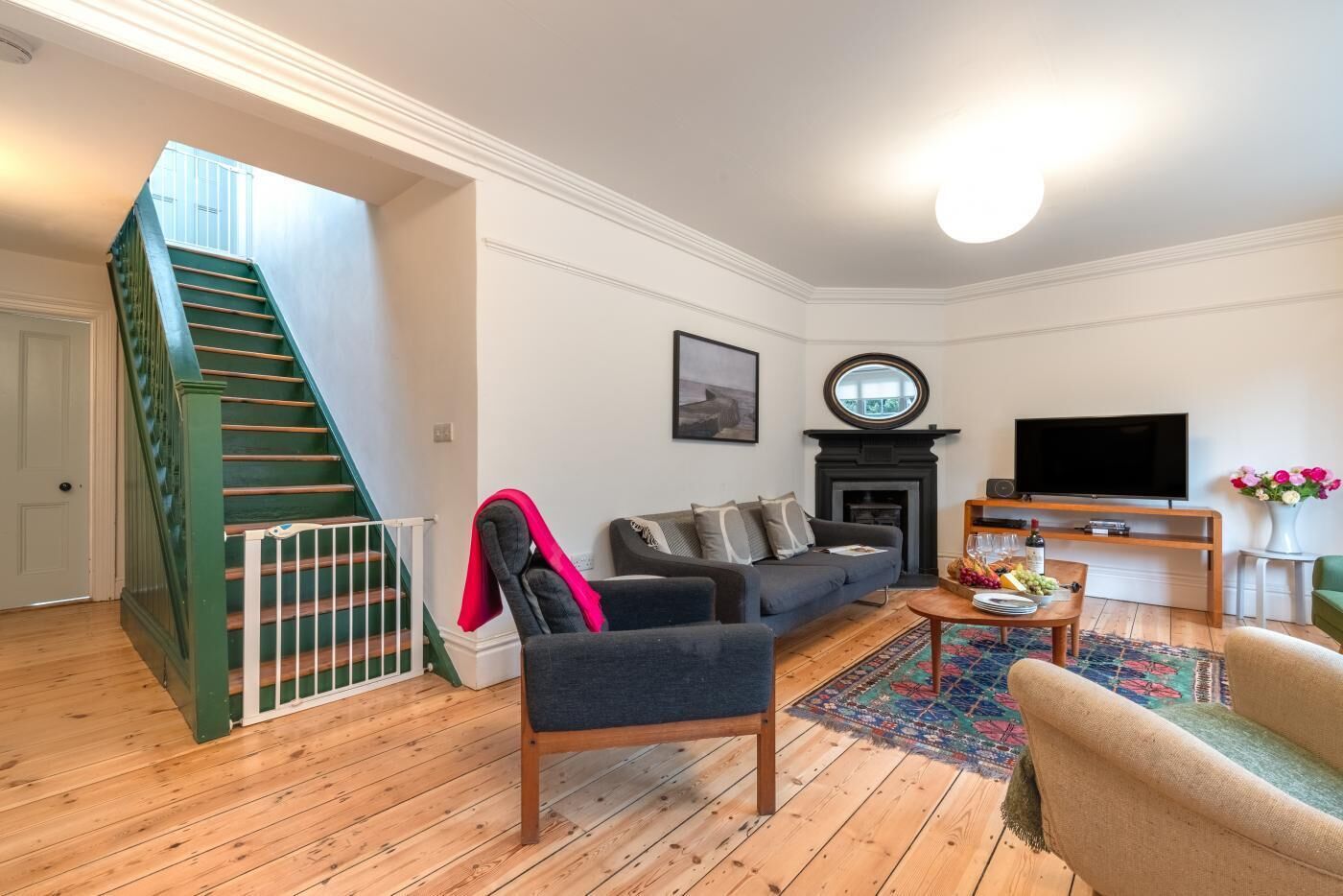 A living room with a staircase, a fireplace, a TV, and a coffee table.