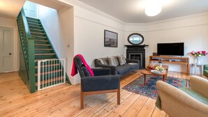 Ein Wohnzimmer mit Treppe, Kamin, Fernseher und Couchtisch.