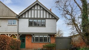 Ein zweistöckiges Haus mit Satteldach, einer grünen Tür und einer Ziegel-Fassade.