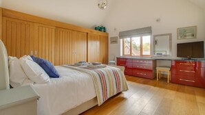 Ein Schlafzimmer mit Bett, Holzschrank, Schreibtisch und Stuhl sowie einem Fenster.