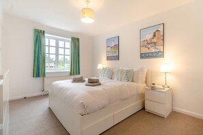 A bedroom with a bed, two bedside tables, a window with curtains, and two wall-mounted pictures. - 5 Bed in Walberswick (oc-hlodg2) (Walberswick)