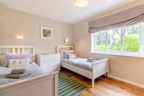 Une chambre avec deux lits, une fenêtre donnant sur un beau paysage et une petite table.