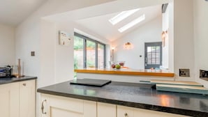 Een moderne keuken met een zwart aanrecht, witte kasten, een raam met uitzicht en een ingebouwde oven.