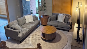 A modern living room with two grey sofas, a wooden coffee table, a chandelier, and a television. - Modern with traditional style 3-bed+ condo, wifi laundry in charming Laurel Oaks (Lima)