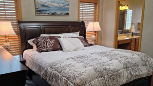 A bedroom with a large bed, two bedside lamps, a chandelier, a painting, and a mirror. - Modern with traditional style 3-bed+ condo, wifi laundry in charming Laurel Oaks (Lima)